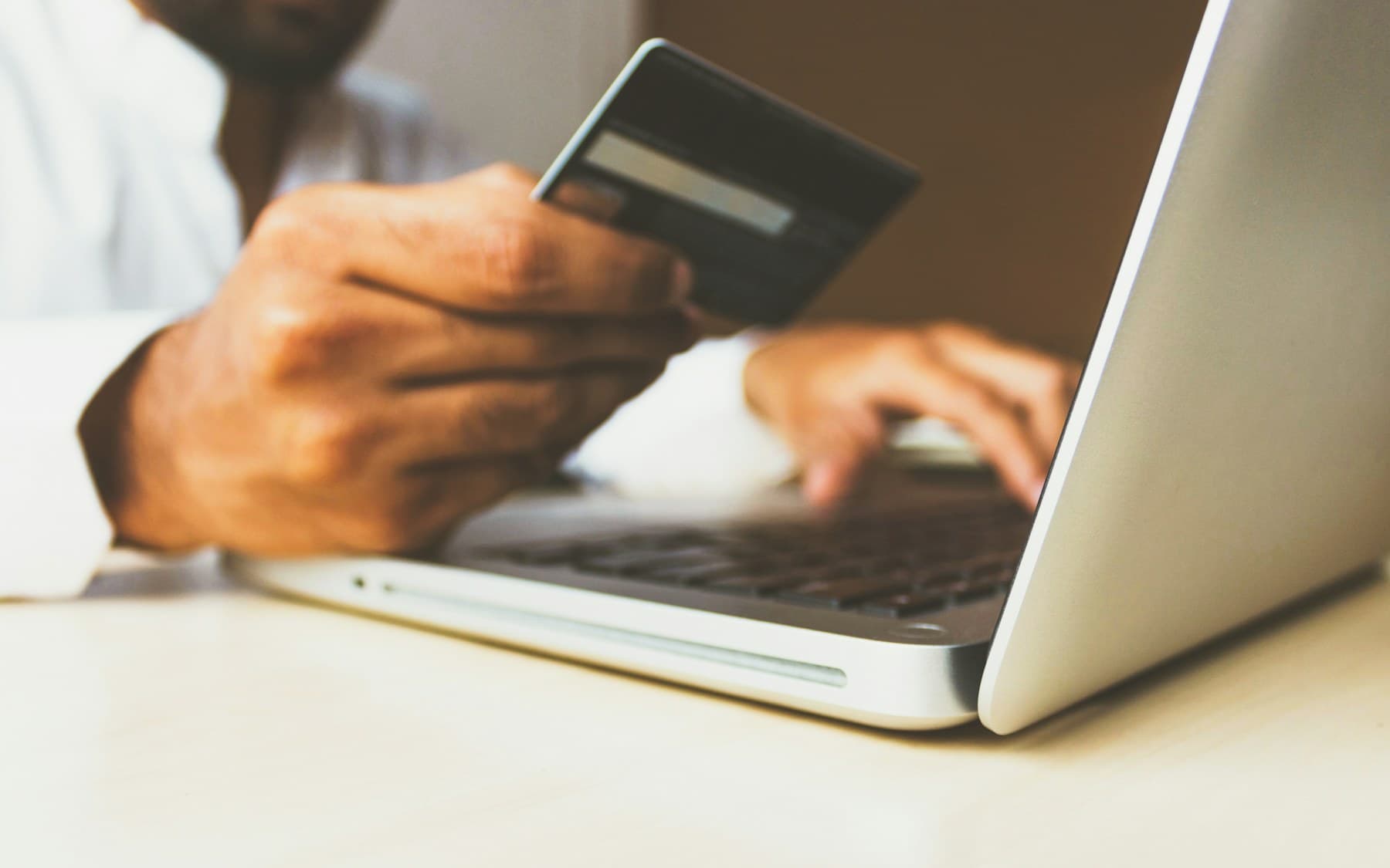 A person holding a credit card while using a laptop